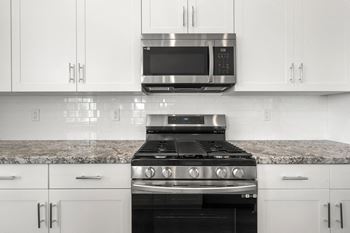 a kitchen with white cabinets and a black stove top oven